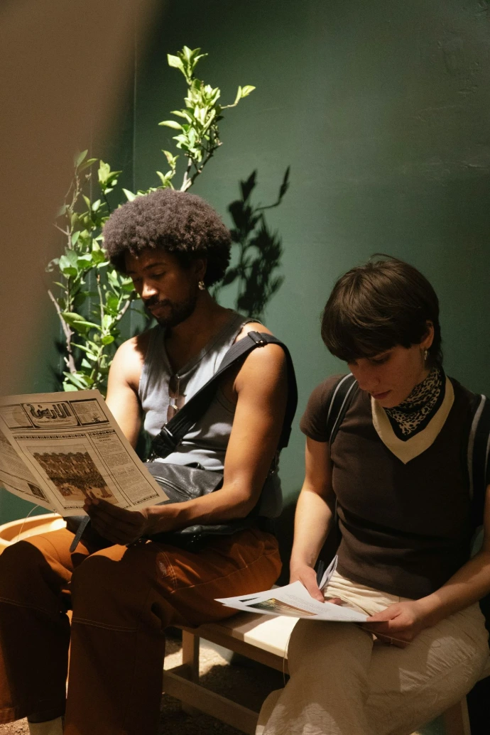 Two people sitting and reading newspapers
